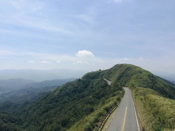 Road leading towards mountain range against sky