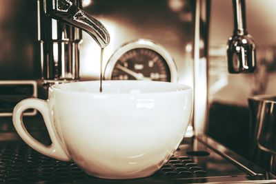 Close-up of espresso pouring in cup from coffee maker