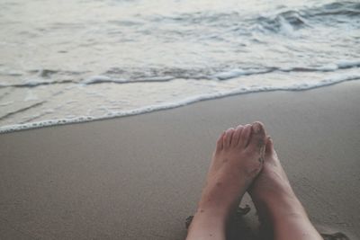 Low section of woman relaxing at beach