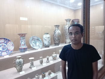 Portrait of young man standing against glass