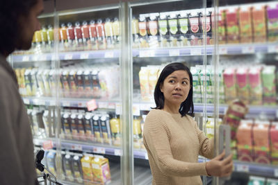 Couple standing in supermarket and talking while shopping