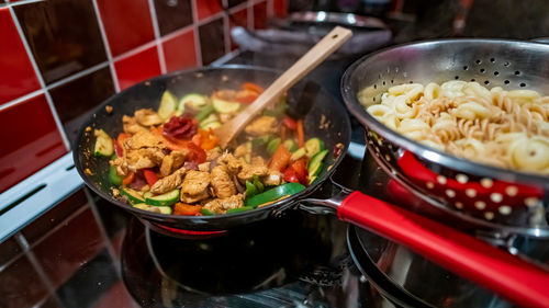 Close up and selective focus of a spicy chicken dish cooking in a non-stick wok on the oven hob