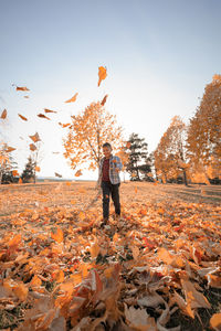 Man standing by leaves on field against sky during autumn