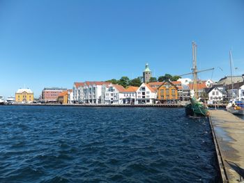 Sea by city against clear blue sky