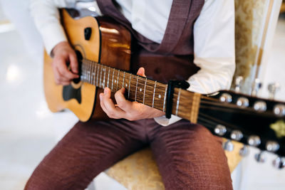 Midsection of man playing guitar