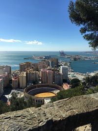 High angle view of buildings and sea against blue sky