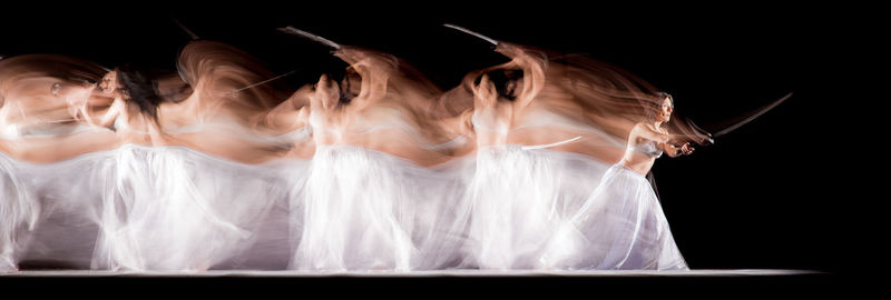 Blurred image of woman holding sword against black background