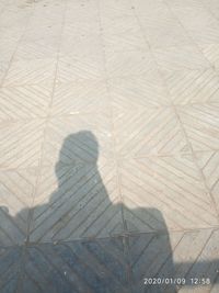 High angle view of woman shadow on tiled floor