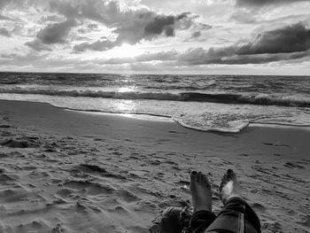 Low section of person on beach against sky