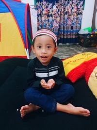 Portrait of cute boy sitting on sofa at home