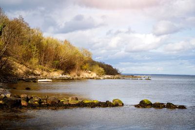 Scenic view of lake and green landscape against cloudy sky