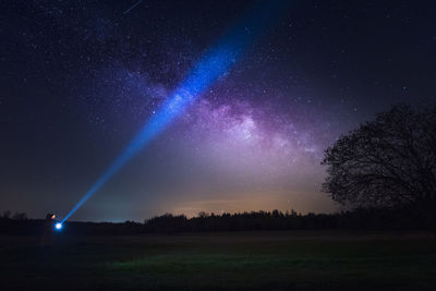 Low angle view of person illuminating the night sky and the milky way/galactic core with torch