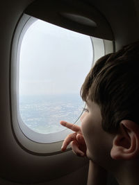 Opening of borders concept. kid looks and points to the landscape from the window of a flying plane.