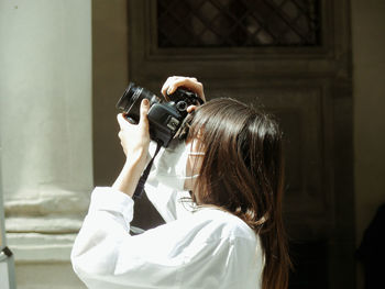 Side view of woman photographing with camera