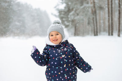 Portrait of cute little girl having fun playing outdoor during snowfall. 