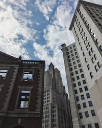 Low angle view of skyscrapers against cloudy sky