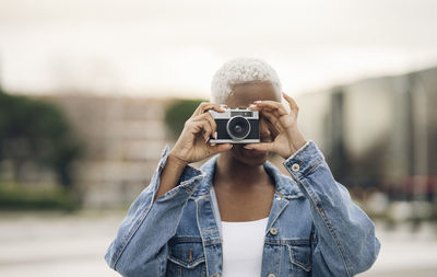 Young woman photographing through old camera