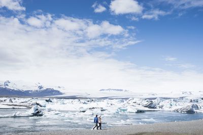 Two people walking by frozen lake