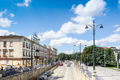 High angle view of road by buildings in city against cloudy sky