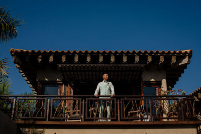 Man against building against clear blue sky