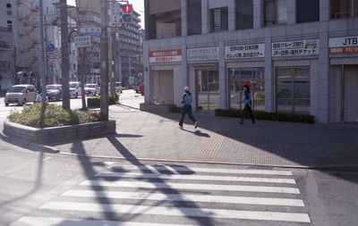 People walking on footpath by buildings in city