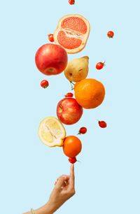 Low angle view of hand holding fruits against white background