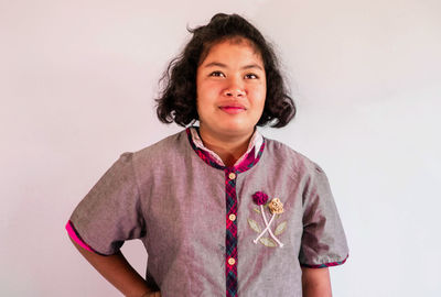 Portrait of young woman standing against white background