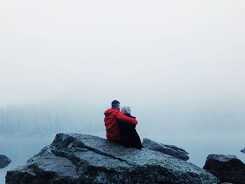 Rear view of man looking at rock against sky