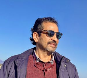 Low angle view of young man standing against clear blue sky