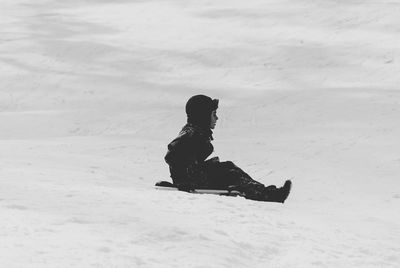 Side view of boy tobogganing on snow