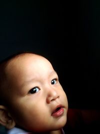 Close-up portrait of cute baby against black background