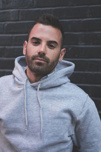 Portrait of young man standing against wall