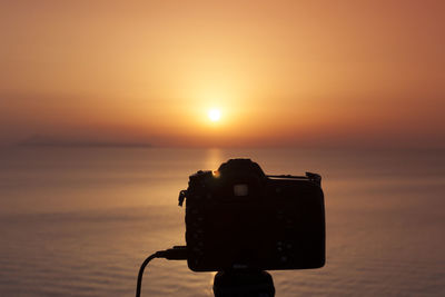 Close-up of camera against sky during sunset