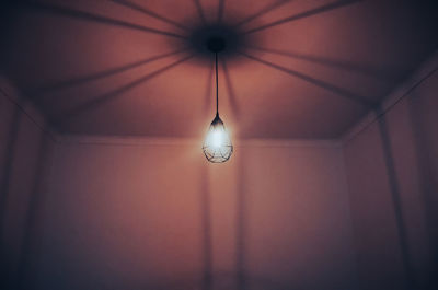 Low angle view of illuminated pendant light hanging on ceiling