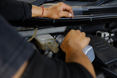 Cropped hand of man pouring oil in car