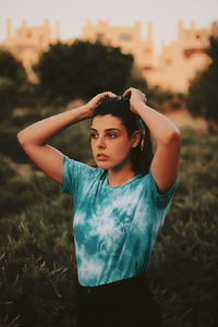 Young woman standing on field at sunset