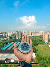 View of cityscape against sky with compass in hand