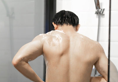Rear view of shirtless man in bathroom