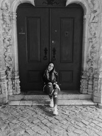 Full length of woman sitting against door