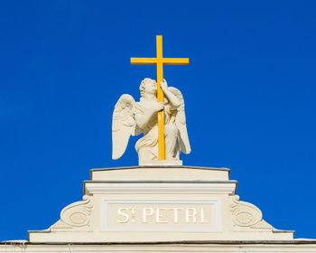 Low angle view of statue against blue sky and building