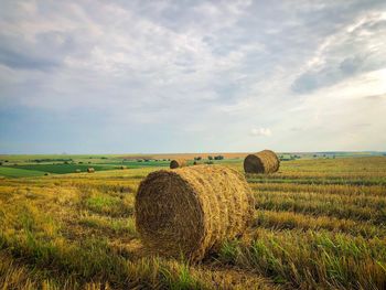 Hay bales on field against sky