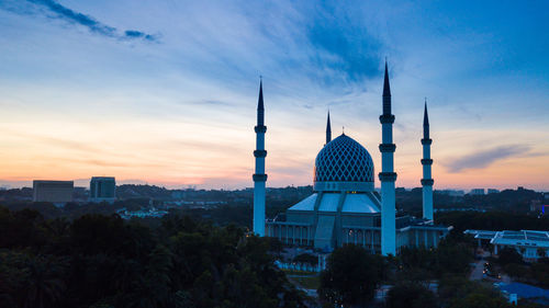 View of mosque amidst city at sunset