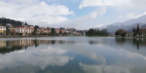 Scenic view of lake by buildings against sky