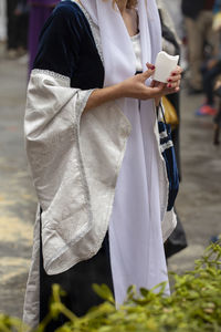 Midsection of woman holding umbrella standing outdoors