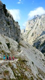 People on rocks against mountains