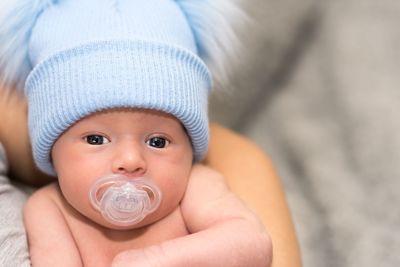 Close-up portrait of cute baby boy with pacifier in mouth