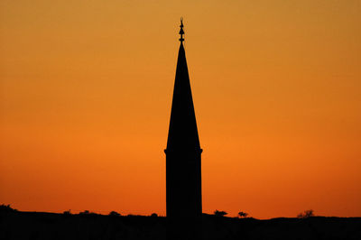 Silhouette of building against orange sky