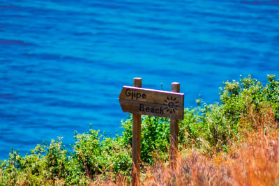 Information sign by sea against blue sky