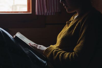 Woman reading book on bed in wooden cottage