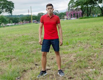 Full length portrait of young man standing on field